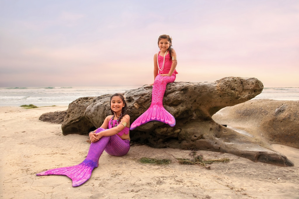 Two mermaids sitting on a rock in San Diego