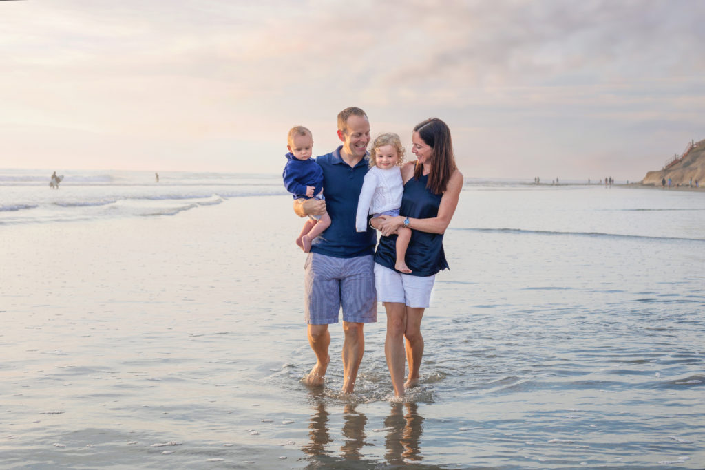 Mother and father walking on a San Diego beach with their children