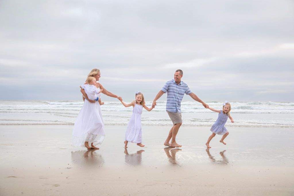 Family holding hands along the beach in San Diego