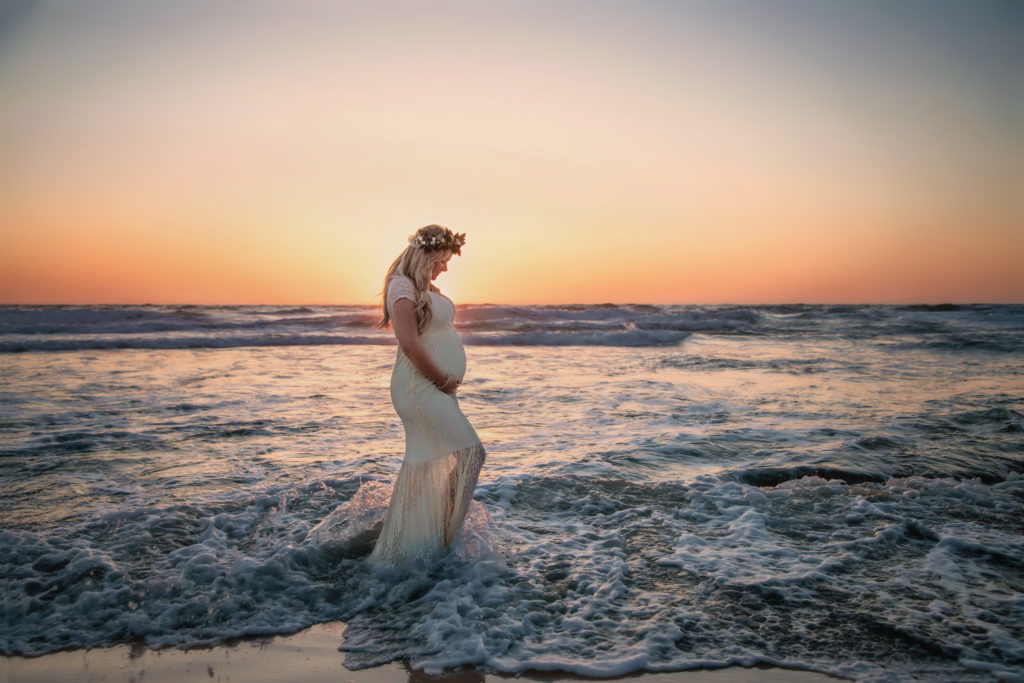 Pregnant mother at sunset posing in the waves in San Diego