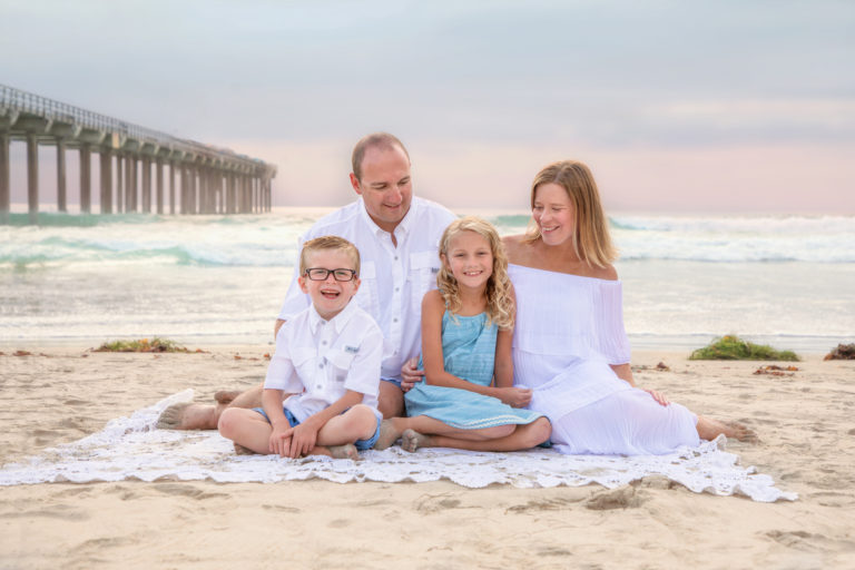 Family sitting on the beach at Scripps Pier in La Jolla