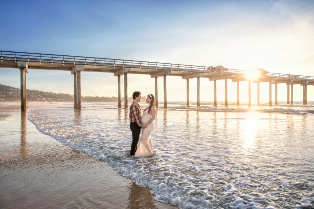 Husband and wife in the waves at Scripps Pier at sunset