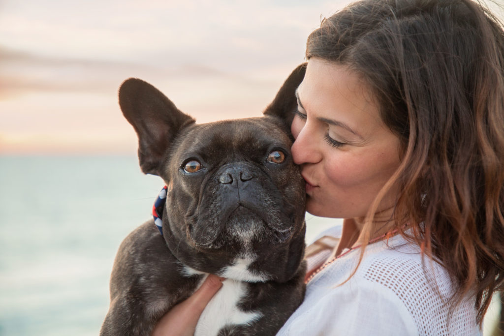 Woman kissing her French bulldog.