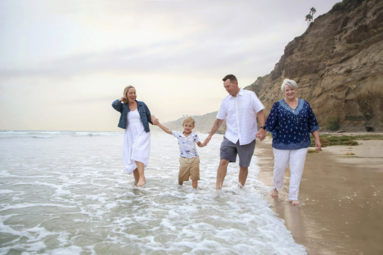 Extended Family Walking Along Beach At Scripps Pier